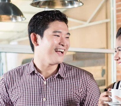 Couple laughing while on a date in a coffee shop.