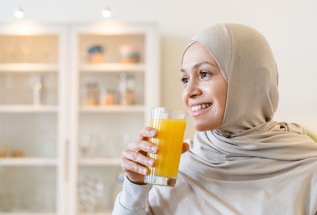 Woman in hijab drinking orange juice