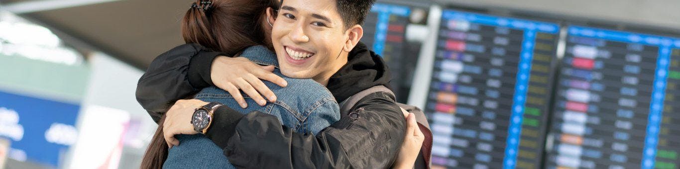 A man smiling while hugging his partner.