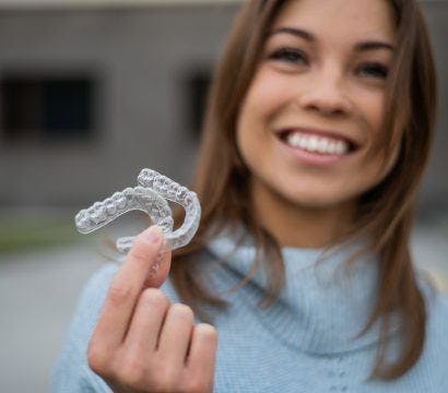 Woman holding out aligners.