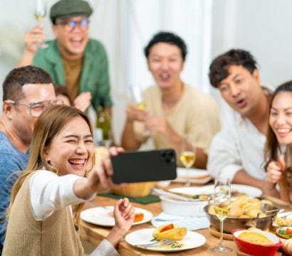 A group of people taking a photo at a table with food.