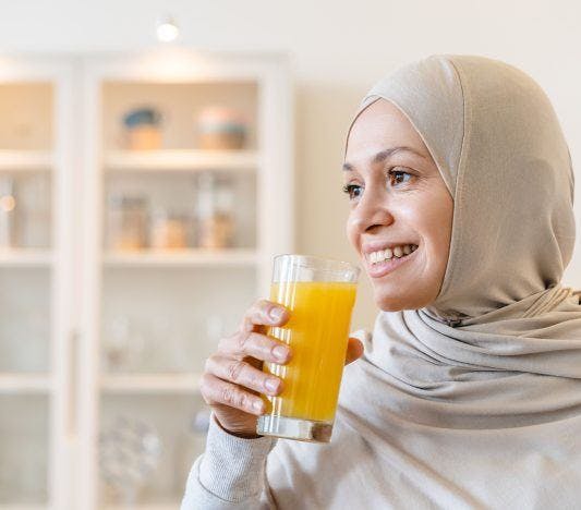 Woman in hijab drinking orange juice
