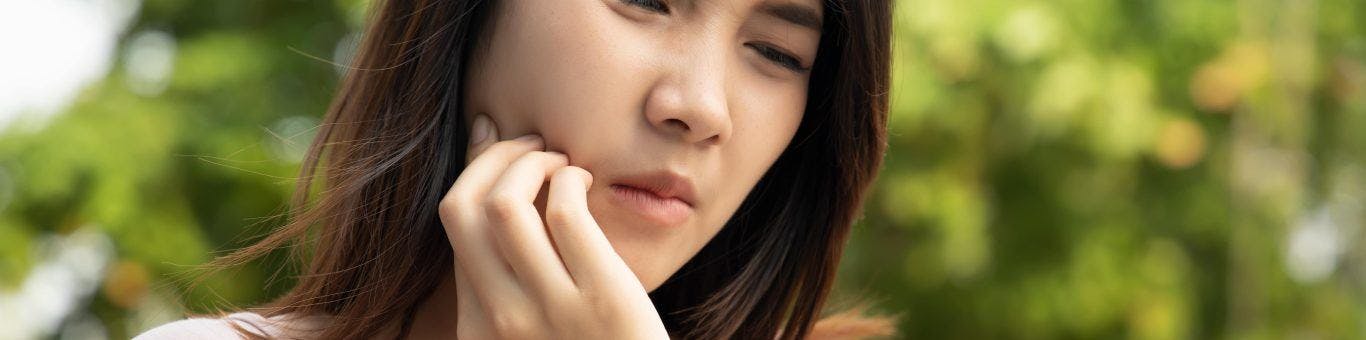 Asian woman holding face with tooth pain.