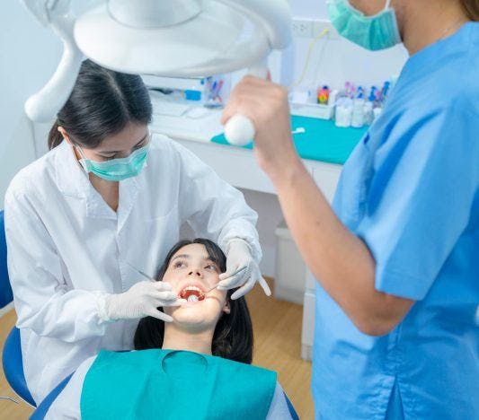 A woman getting her tooth extracted by a dentist.