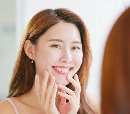 A woman with healthy teeth smiling in front of the mirror.