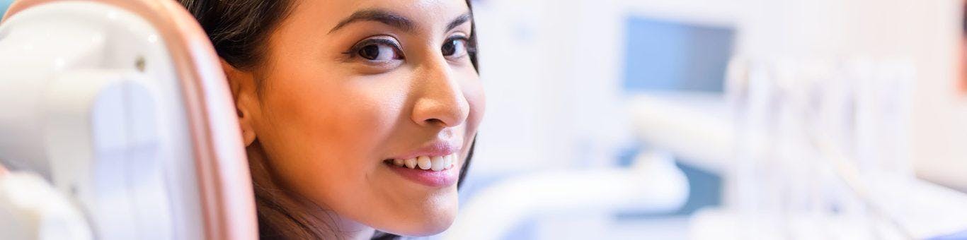 A young mixed-race woman smiles while waiting in a clinic.