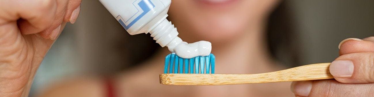 A woman squeezing out toothpaste onto toothbrush.