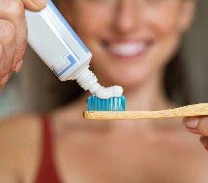 A woman squeezing out toothpaste onto toothbrush.