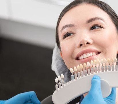 Orthodontist picking crowns for a smiling female patient before dental implants.