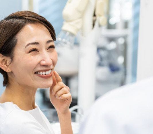 A smiling woman consulting a dentist.