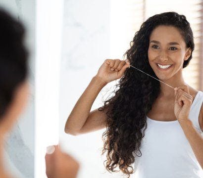 A woman flossing in front of the mirror.