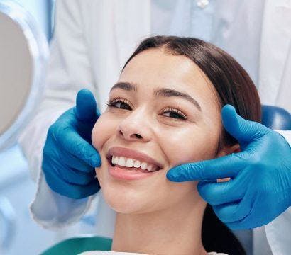 Woman smiling at the dentist holding a hand mirror.
