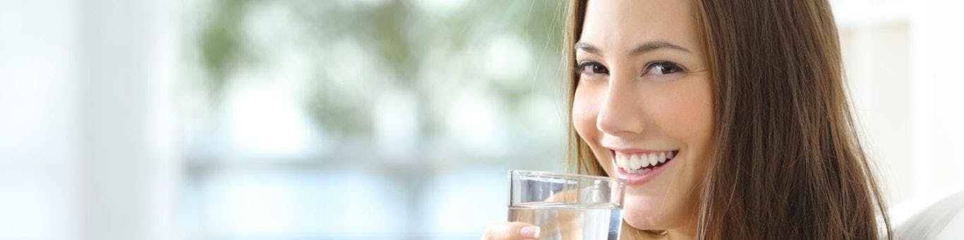 Woman smiling and holding a glass of water.