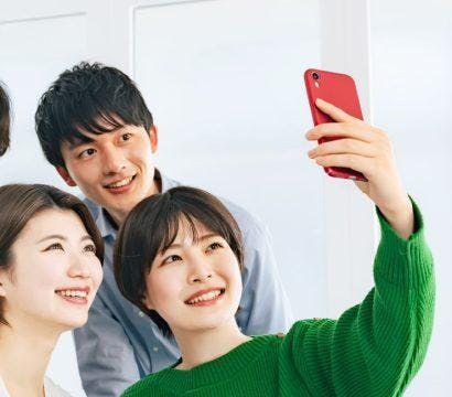 Four friends taking a selfie and smiling in a bright living room.