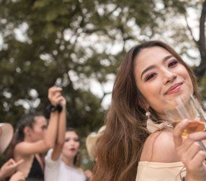 Smiling woman holding a wine glass at an outdoor party.