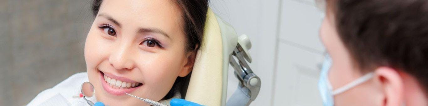 Female dental patient in a dentist’s chair smiling.