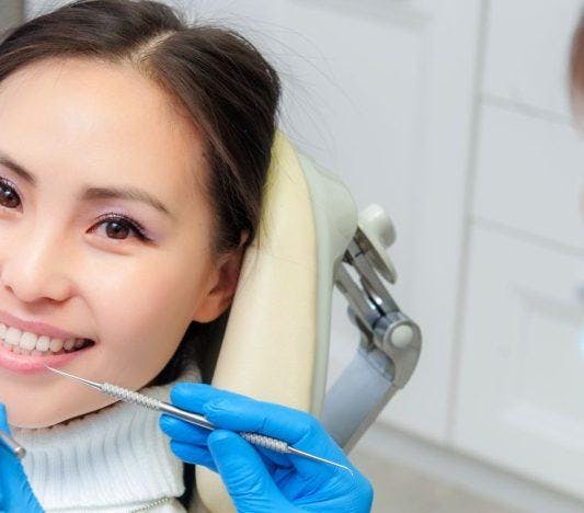 Female dental patient in a dentist’s chair smiling.