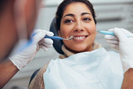 Mixed race woman smiling while having her teeth cleaned. 