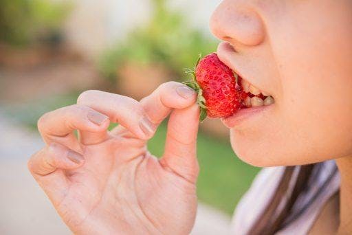 A close-up of a young woman eating strawberry