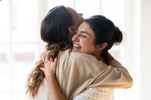 A woman happily hugging another woman.