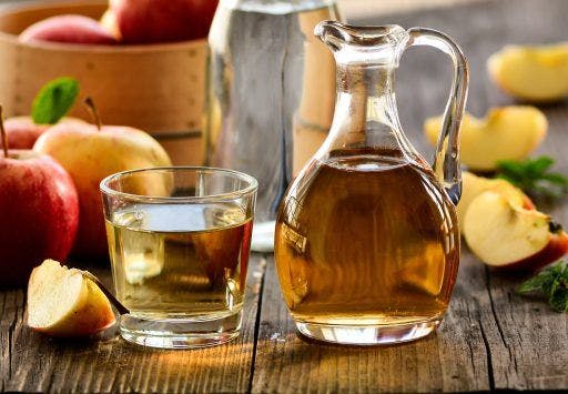 A pitcher and a glass of apple cider vinegar. 