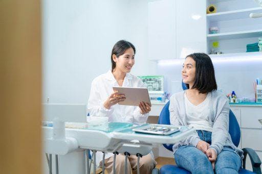 Asian female dentist and patient smiling during a consultation.