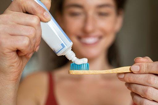 Woman squeezing toothpaste onto toothbrush.