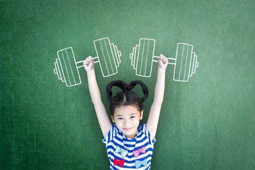 Little girl smiling and holding her arms up against a green background with a drawing of barbels.