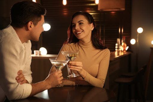 Woman staring into man’s eyes with martini glasses on the table.