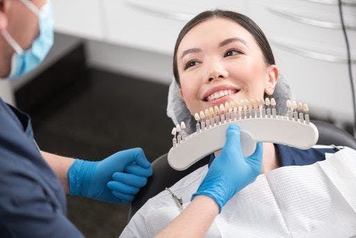 An Asian woman getting her teeth colour reviewed by a dentist. 