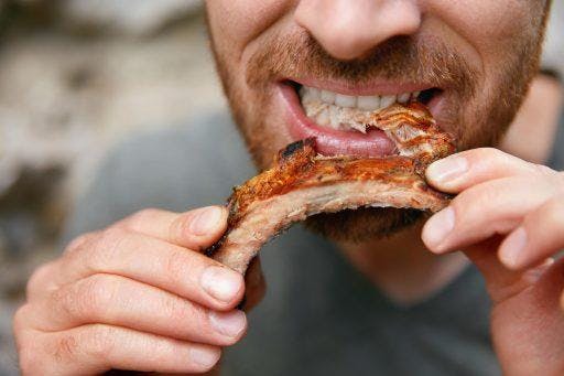 Man eating barbecued ribs.