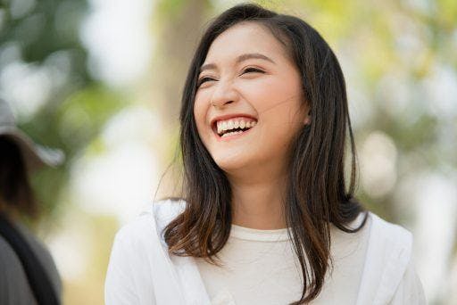 An Asian woman smiling with teeth.