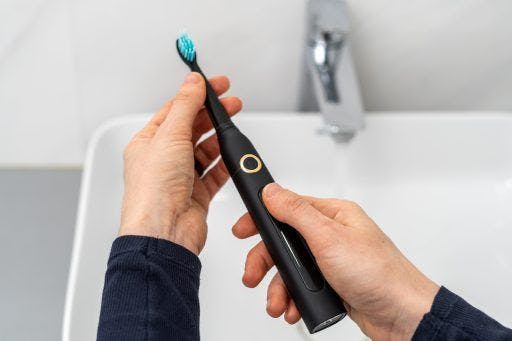 Two hands holding a black electric toothbrush.