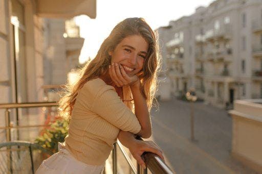 Beautiful woman smiling on balcony against the sun.