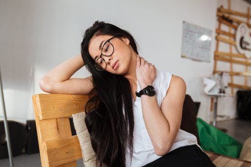 Asian woman with glasses and long hair stretching her neck. 