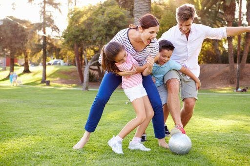 Family happily playing football in a field. 