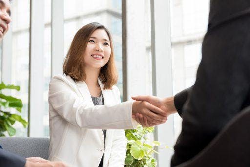 A businesswoman shaking hands with a businessman.