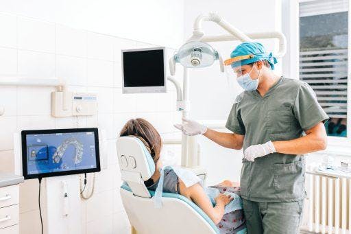 A male dentist explains a procedure with a female patient in a dental clinic.