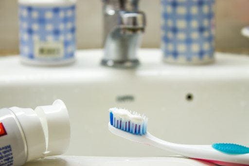 Close-up photo of toothbrush and toothpaste on a bathroom sink. 
