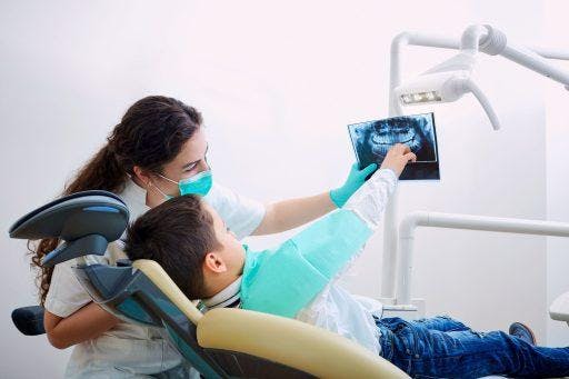 A boy and his dentist check teeth x-ray during a dental appointment.
