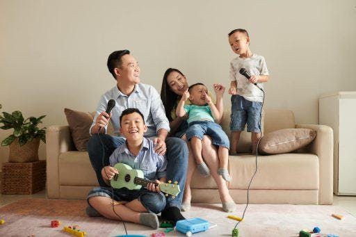 A family singing together while one boy plays the guitar.