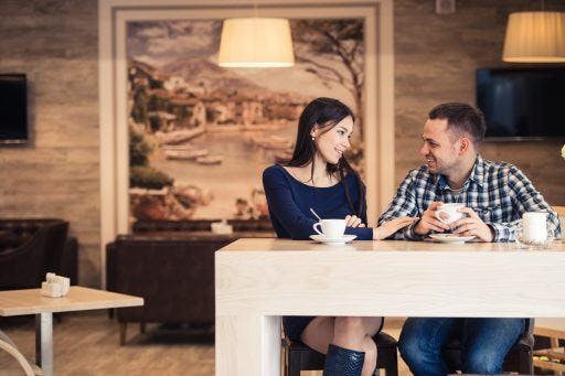 A man and a woman chatting in a coffee shop over drinks.