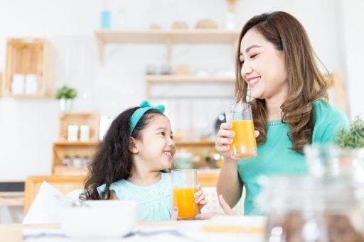 A mom and child drinking orange juice.