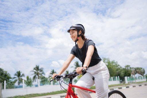 A woman riding a bicycle and wearing a helmet.
