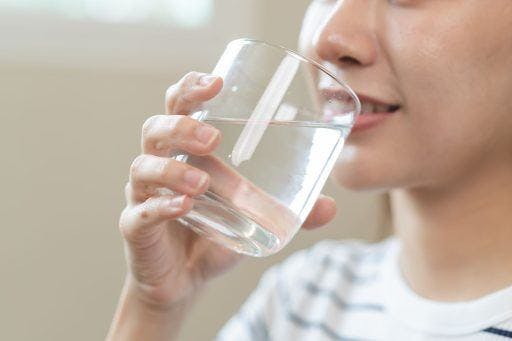 A smiling woman drinking a glass of water.