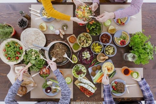 A spread of salads and other wholesome foods on a table shared among friends. 