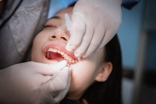 A dentist checks the teeth of a young Asian woman. 