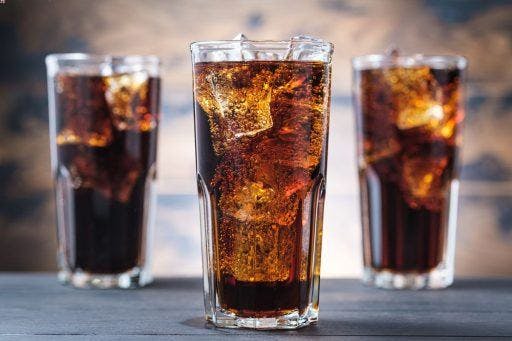Three clear glasses filled with ice-cold soda.