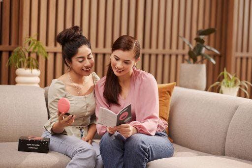 Two girls reading about clear aligners through pamphlets.