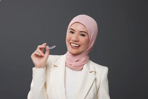 A woman holding her clear aligners. 